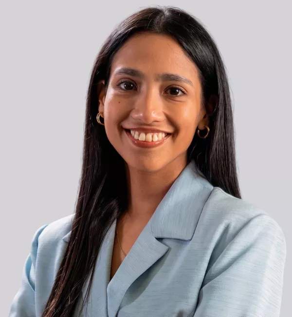 Smiling woman with long dark hair in a light blue blazer, posing for a professional portrait.